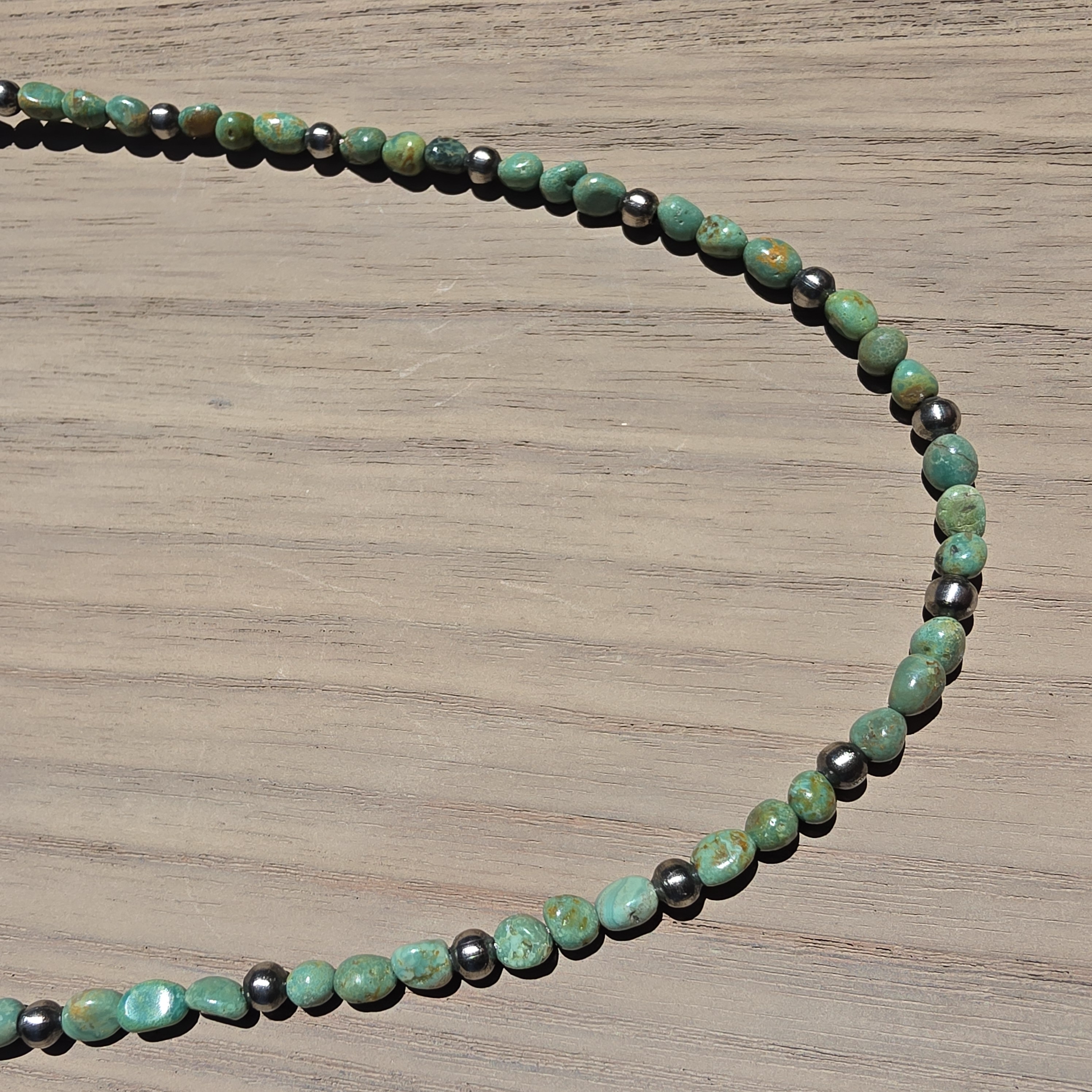 A strand of green desert turquoise beads showing natural brown matrix